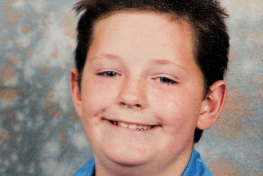 A boy around 10-years-old poses for his school photos.