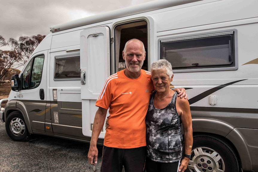 Man and woman standing in front of recreational vehicle.