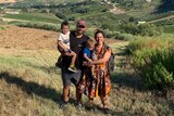 Jarred, Aurora and their two kids stand on a hill in Tuscany