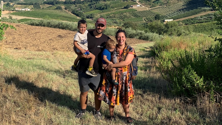 Jarred, Aurora and their two kids stand on a hill in Tuscany