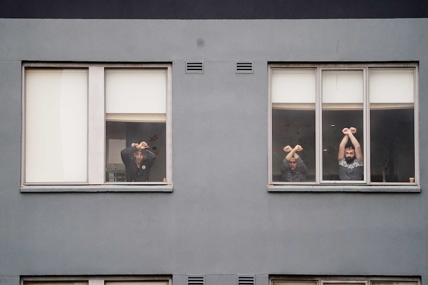Three men are visible through the window of the Mantra hotel in Melbourne.
