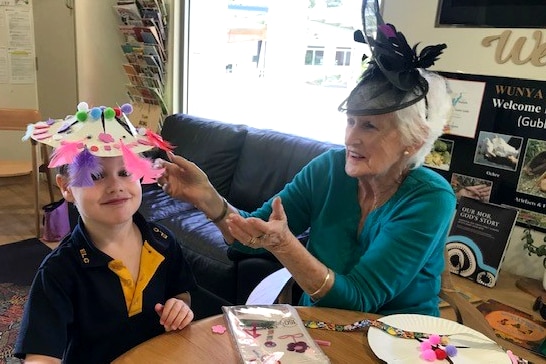 Senior lady helping a small child with craft