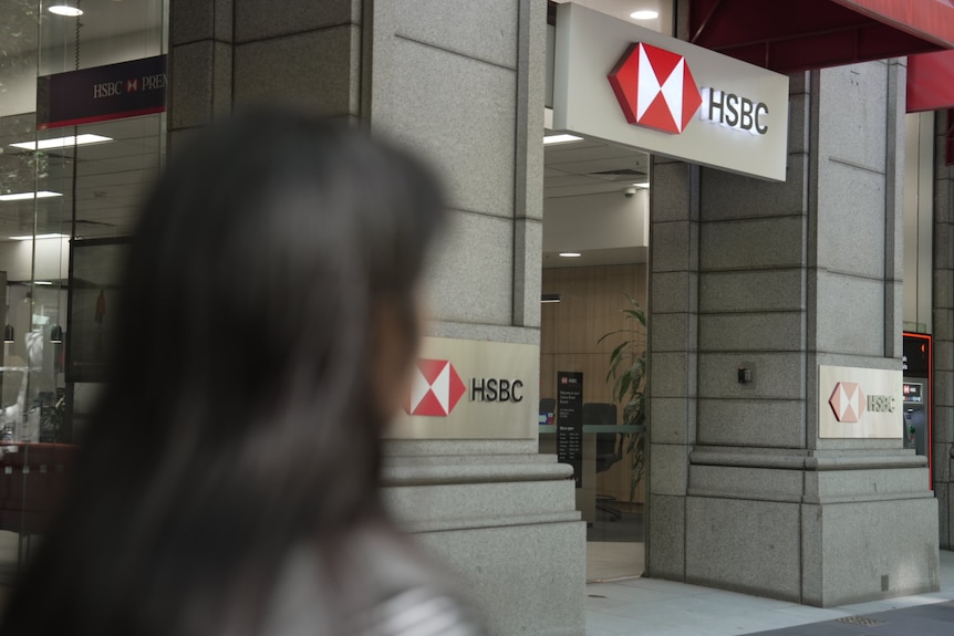 An unidentified Asian woman stands outside an HSBC bank branch. She is shot from behind