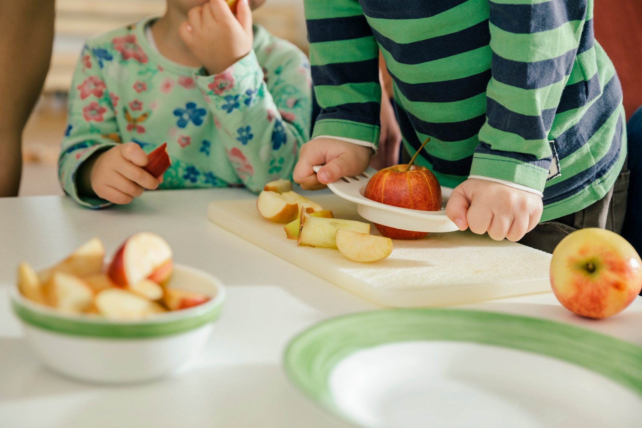 Two toddlers eating apples segments