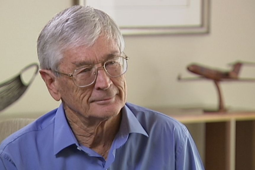 A man with grey hair and glasses sitting in an office