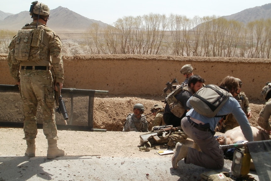 A group of men surround David Savage, who is lying on the ground.