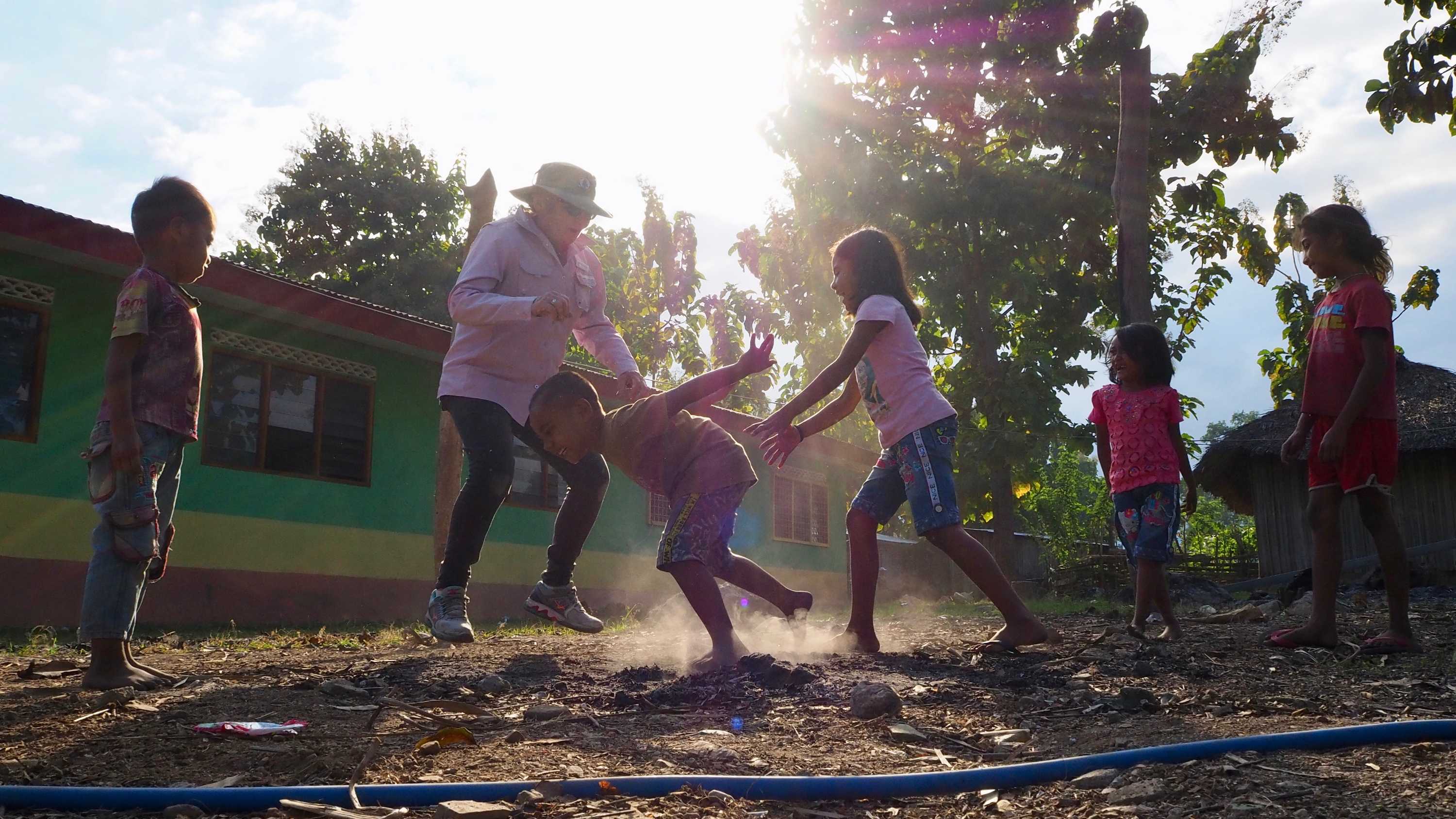 Four children are seen playing outside a building in the glare of the sunshine