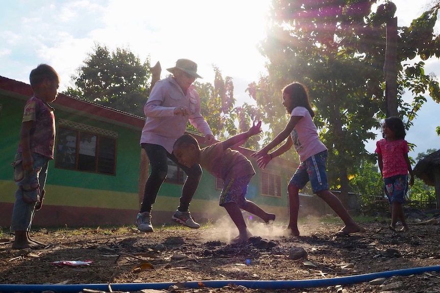 Four children are seen playing outside a building in the glare of the sunshine