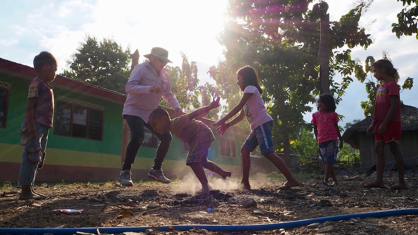 Four children are seen playing outside a building in the glare of the sunshine