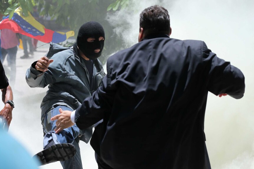 A masked men kicks at opposition politician Franco Casella.