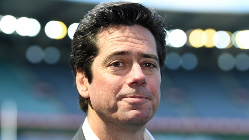 A senior AFL official stands in a stadium looking at the camera.