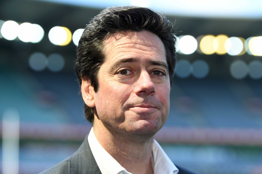 A senior AFL official stands in a stadium looking at the camera.