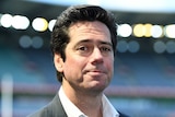 A senior AFL official stands in a stadium looking at the camera.