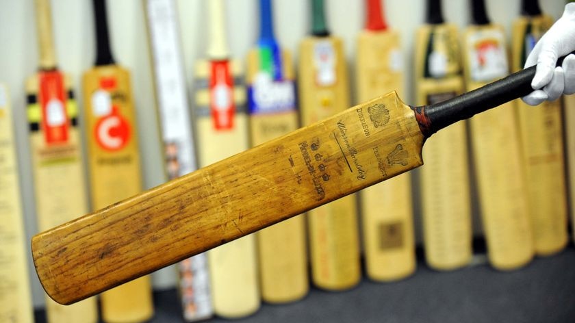 An employee at Leski auction house in Melbourne holds Sir Donald Bradman's first Test cricket bat