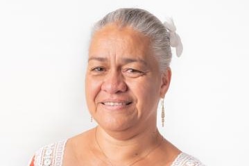 Patricia Goa, a New Caledonian woman wearing a floral dress with a flower in her hair.