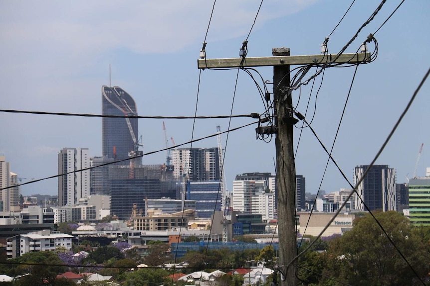 Brisbane city skyline from suburban view with stobie pole and electricity power lines in foreground.