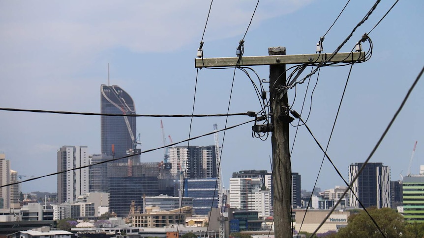 Brisbane city skyline from suburban view with stobie pole and electricity power lines in foreground.