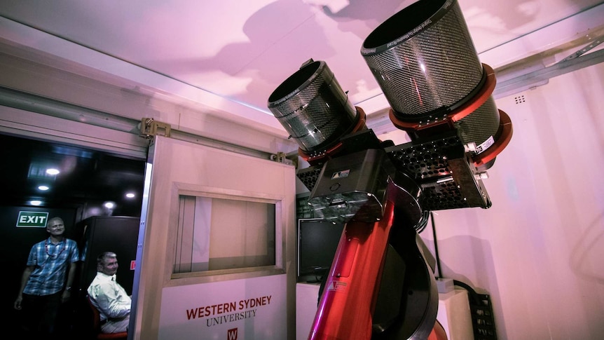 two men looking at a telescope