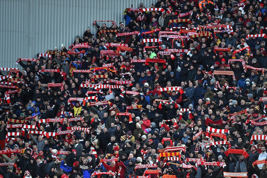 A large Premier League crowd hold up their scarfs