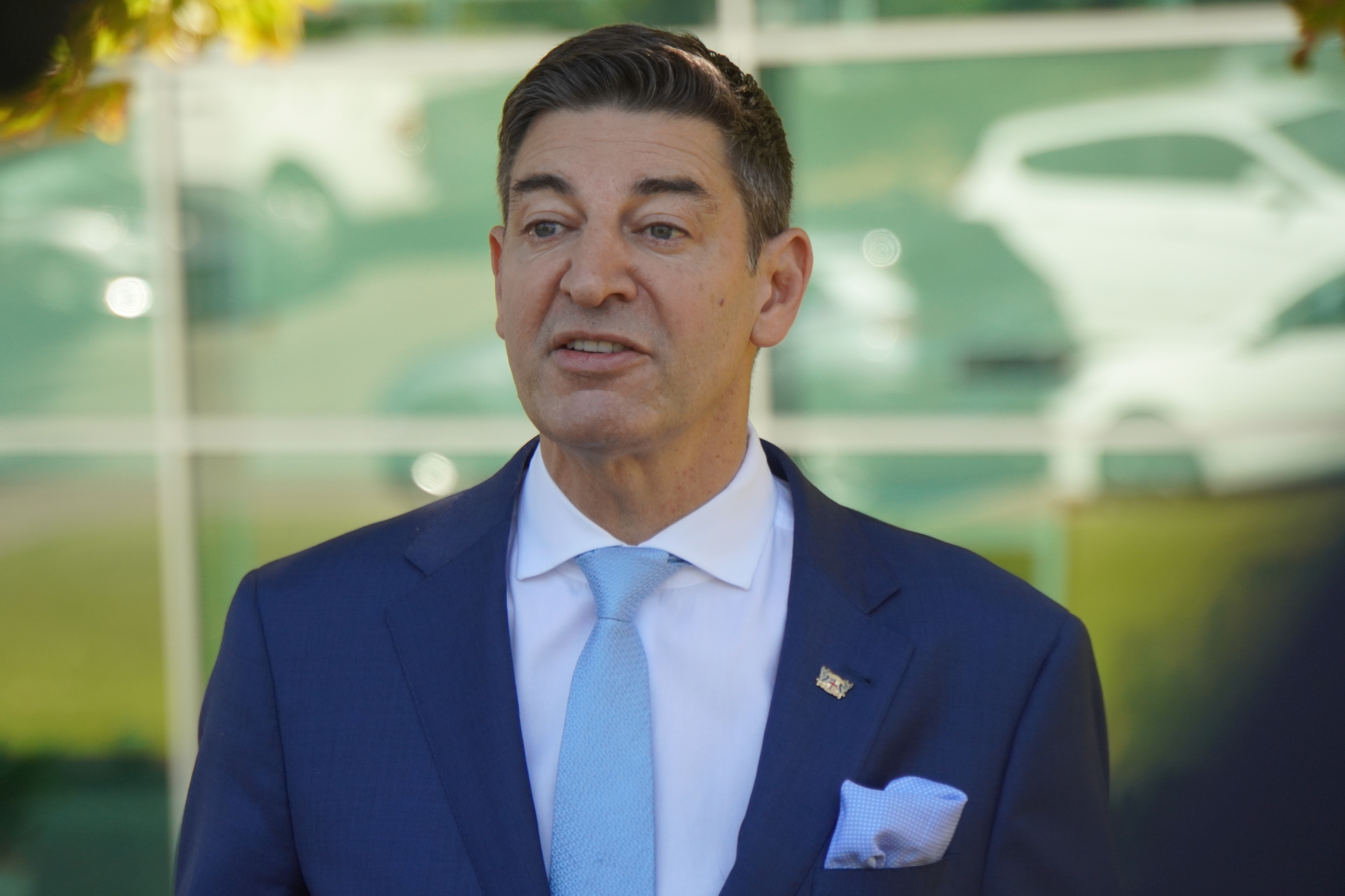 Un hombre de traje se para frente a una ventana.