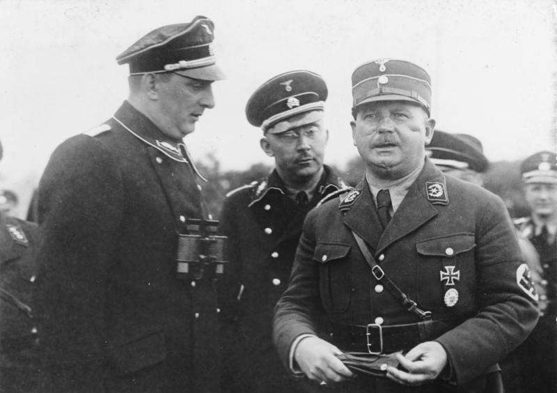 Three men in Nazi military uniform stand together in a black and white photograph
