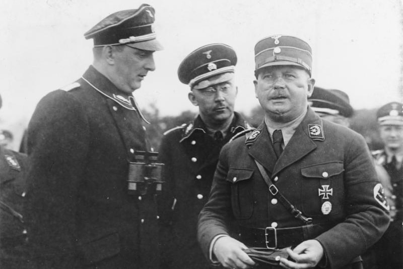 Three men in Nazi military uniform stand together in a black and white photograph
