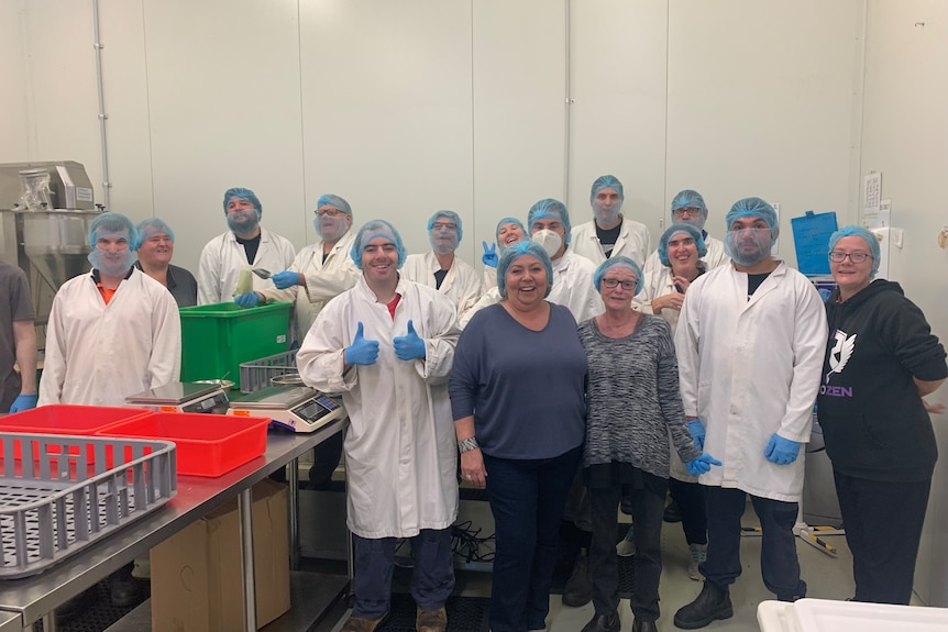 Group photo of packaging workers at factory in white coats and protective masks and head gear Ausnew Home Care, NDIS registered provider, My Aged Care