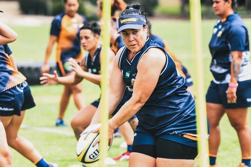 Female rugby player holding a football. 