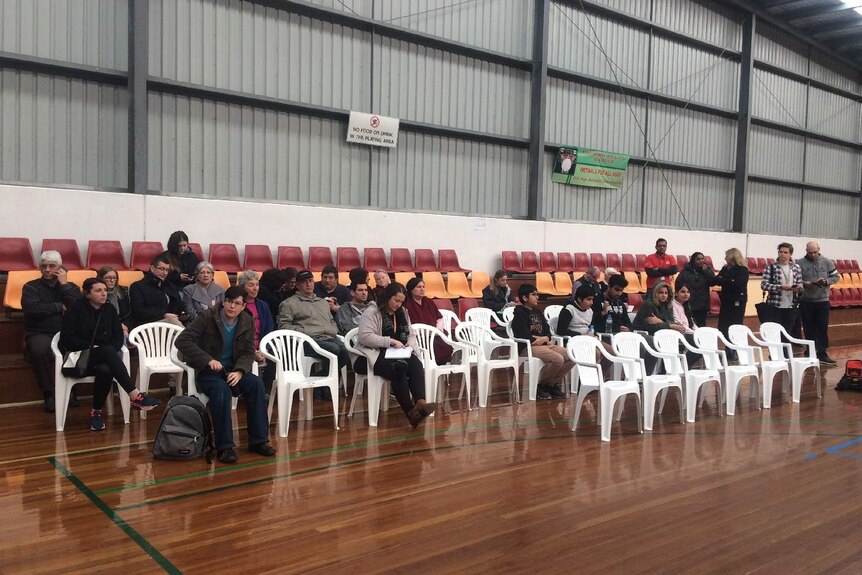 A small crowd gathers at a community meeting in a Broadmeadows sports centre.