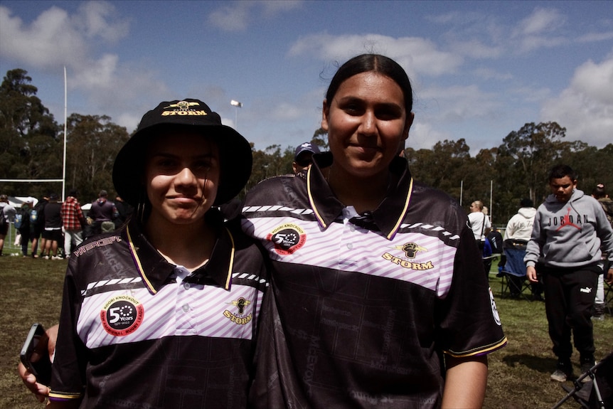 two girls, smiling, wearing black and white rugby league jerseys