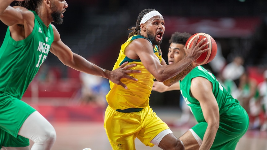 A man wearing a yellow top holds a basketball