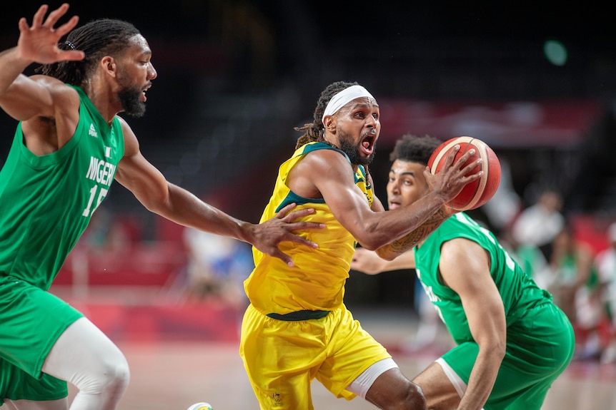 A man wearing a yellow top holds a basketball