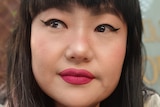A woman with red lipstick, black winged eyeliner and black hair poses for the camera. 
