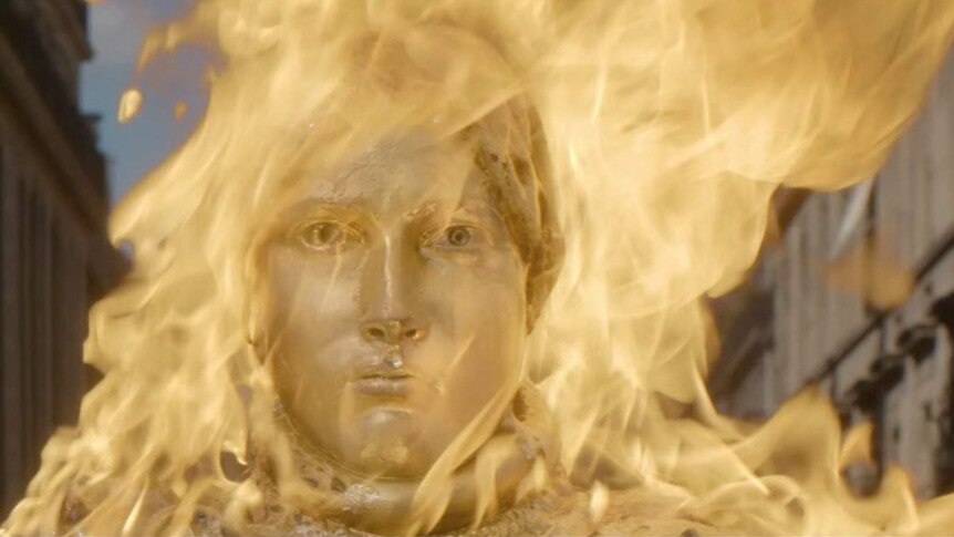 Still colour image of a golden Joan of Arc statue engulfed in flame, from 2016 French film Nocturama