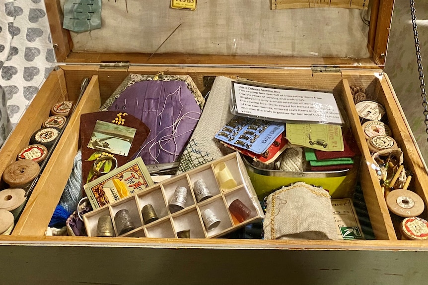 an old sewing box filled with old bobbins and sewing pads