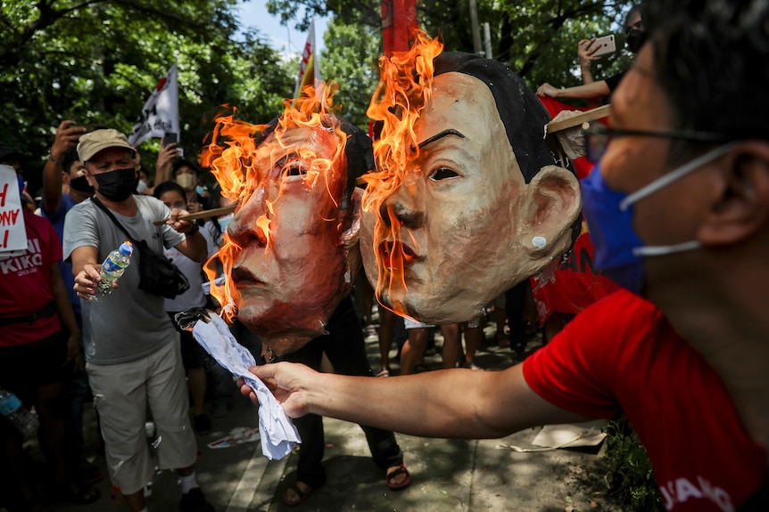 Large face masks in the likeness of Ferninand Macos Jr and Sara Duterte burn.