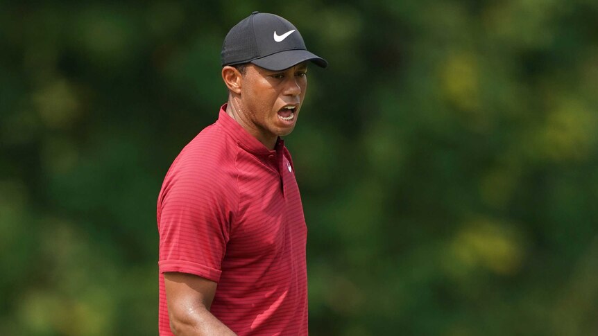 Tiger Woods pumps his fist after making a birdie putt.