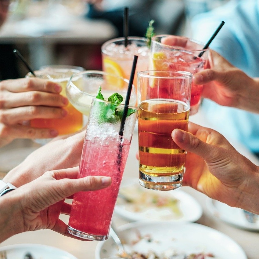 A group of people hold up their alcoholic drinks for a cheers.