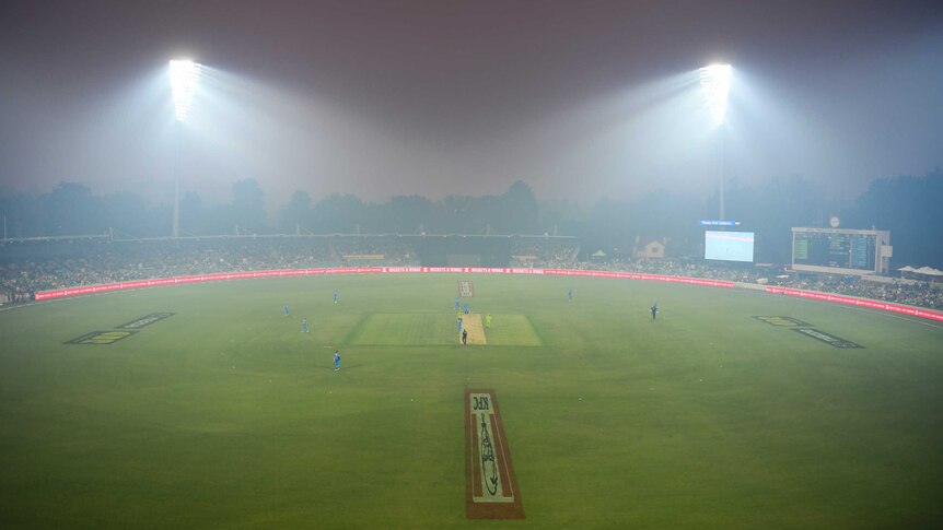 Manuka Oval is seen from a distance as smoke blankets the cricket ground, lit up by floodlights