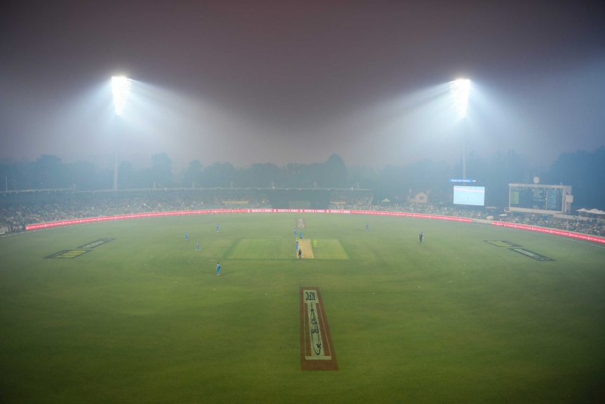 Manuka Oval is seen from a distance as smoke blankets the cricket ground, lit up by floodlights