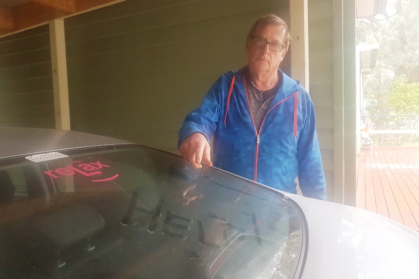 A man stands near a dusty car.