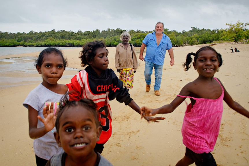 aboriginal kids looking happy on the beach in front of two adults