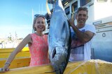 A couple poses with a big tuna.