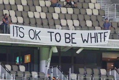 A white banner reading 'It's OK to be white' hanging from one of the stands at Perth Stadium.