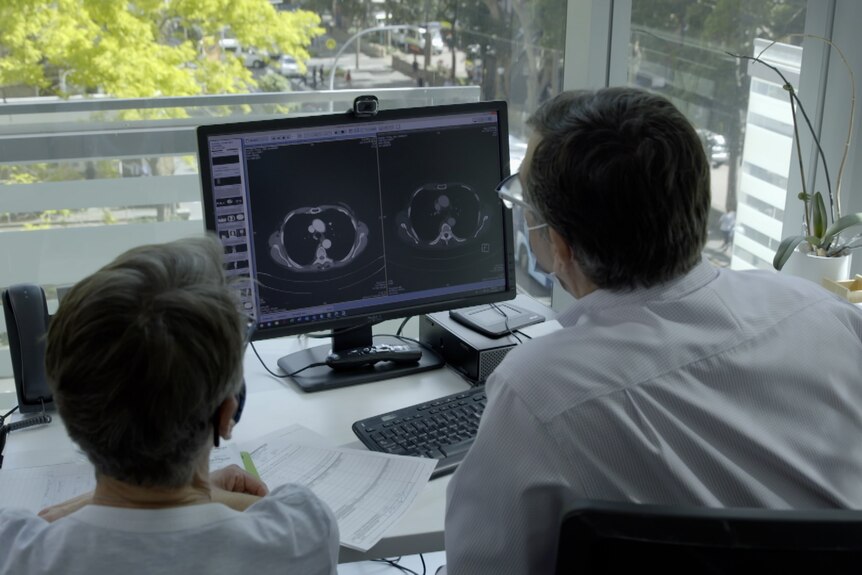 A man and a woman in a doctor's office study some x-ray images