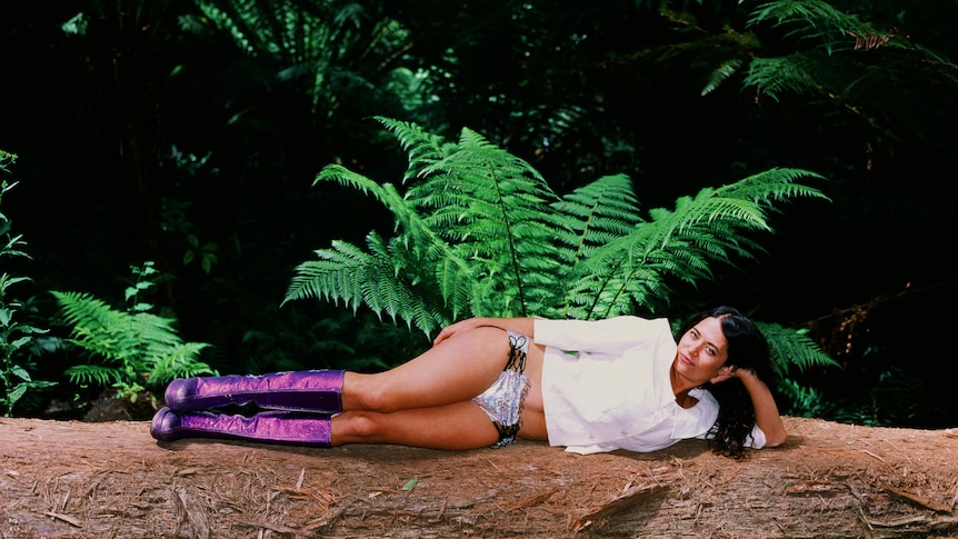 Tori Zietsch, aka Maple Glider, poses in a rainforest wearing purple knee-high boots, silver underwear and white shirt
