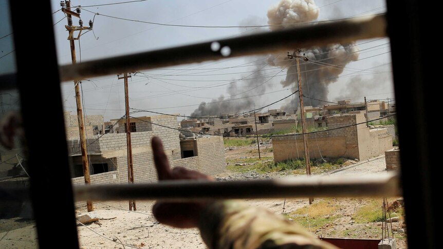 A member of Iraqi Rapid response forces points at an air strike.