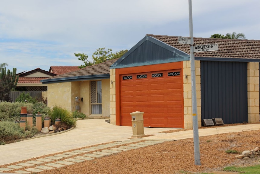 A house with an orange garage, with a street post in front that says "Winchester Way"