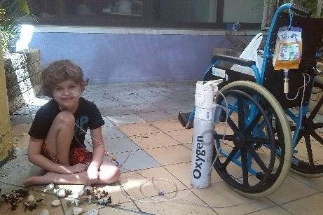 Sean Rice sitting next to oxygen tank and wheelchair