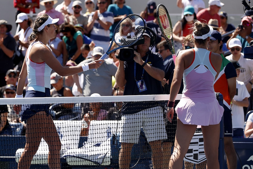 Marta Kostyuk and Victoria Azarenka touch racquets at the net at the US Open.